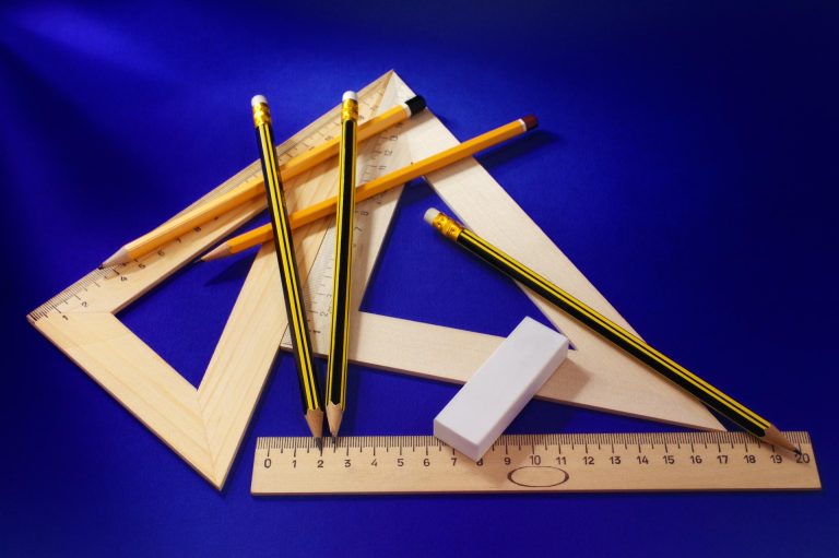 Bleistifte, Radiergummi, Lineal und Geodreiecke auf blauem Grund