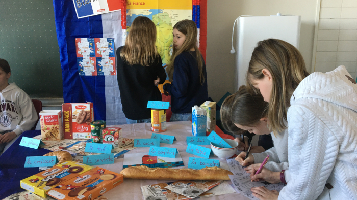 Schülergruppe mit französischem Essen vor sich auf dem Tisch