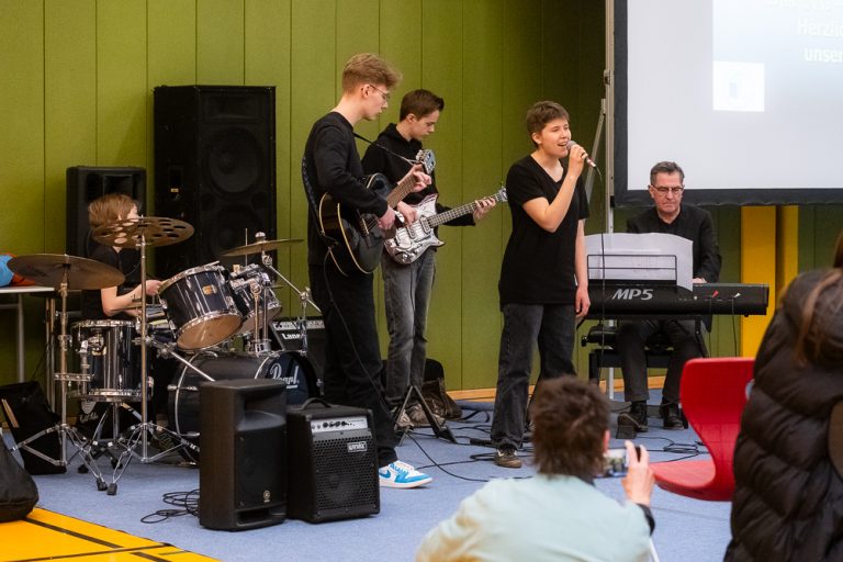 Schülerinnen und Schüler der Schulband treten in der Sporthalle auf