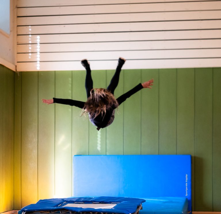 Schülerin macht Salto über Matten in der Sporthalle