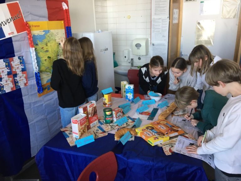 Schülergruppe vor französischen Lebensmitteln und an einer Landkarte