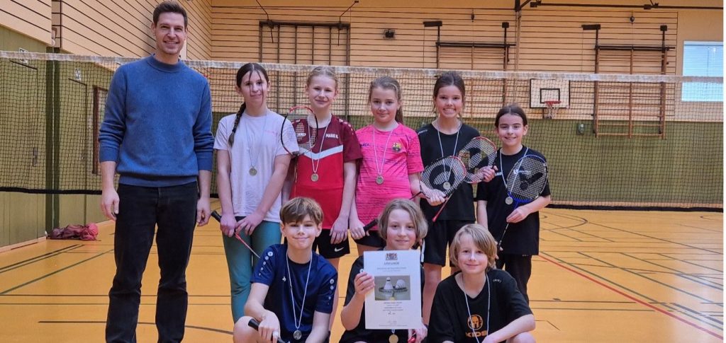 Sportlehrer und Schülerinnen und Schüler mit Urkunde am Ende des Badminton-Bezirksfinales