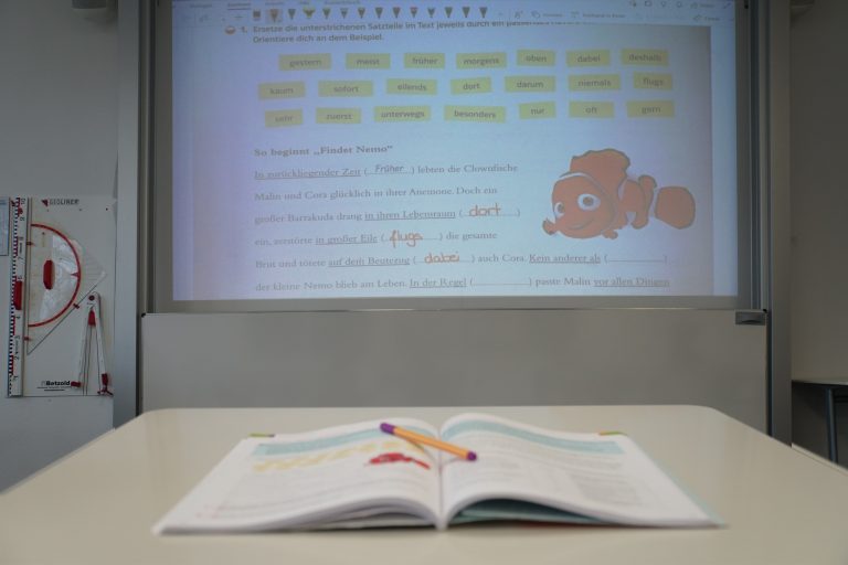 Bild aus einem Klassenzimmer mit Heft und digitaler Tafel