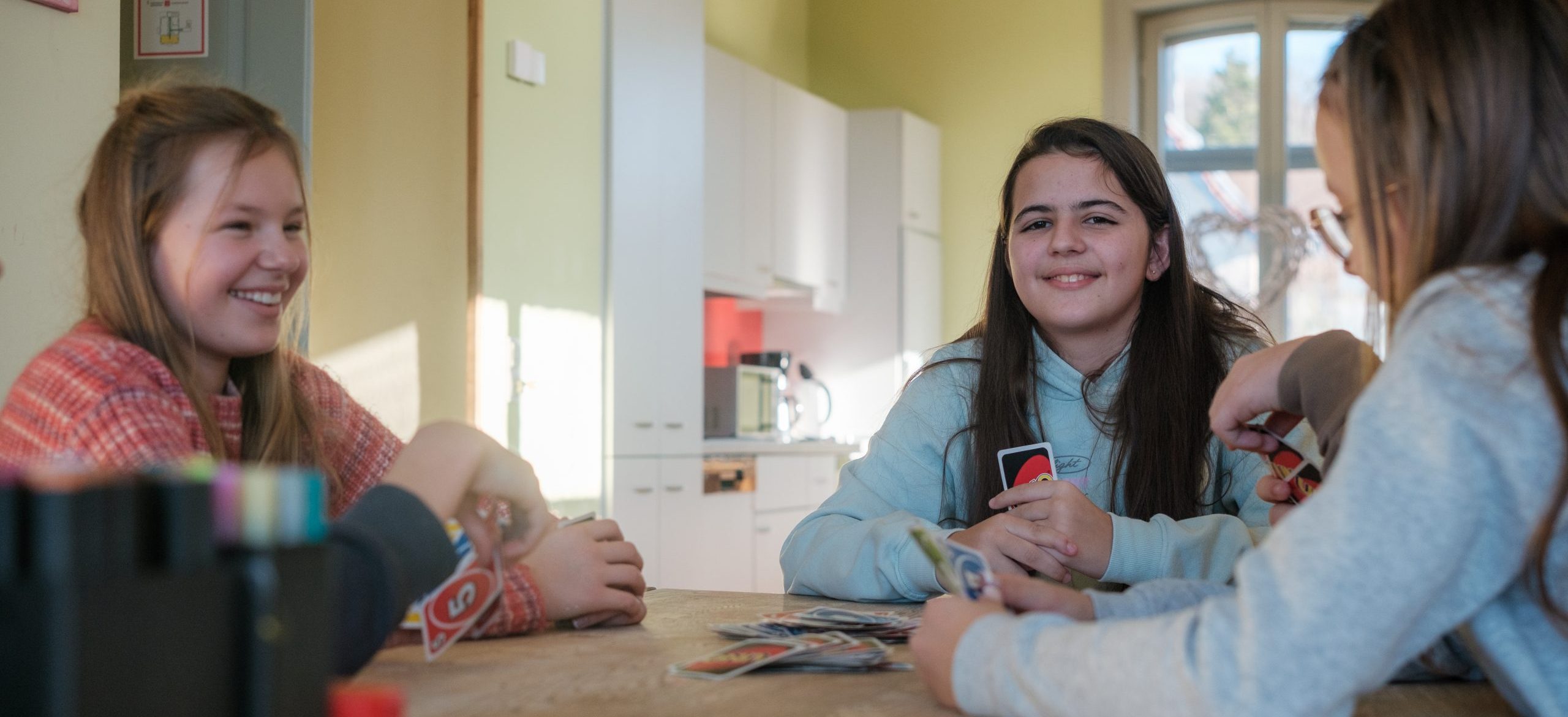 Schülerinnen und Schüler spielen UNO an einem Tisch in den Räumen der offenen Ganztagsbetreuung