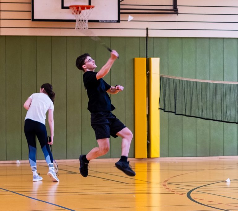 Schüler springt beim Badminton spielen