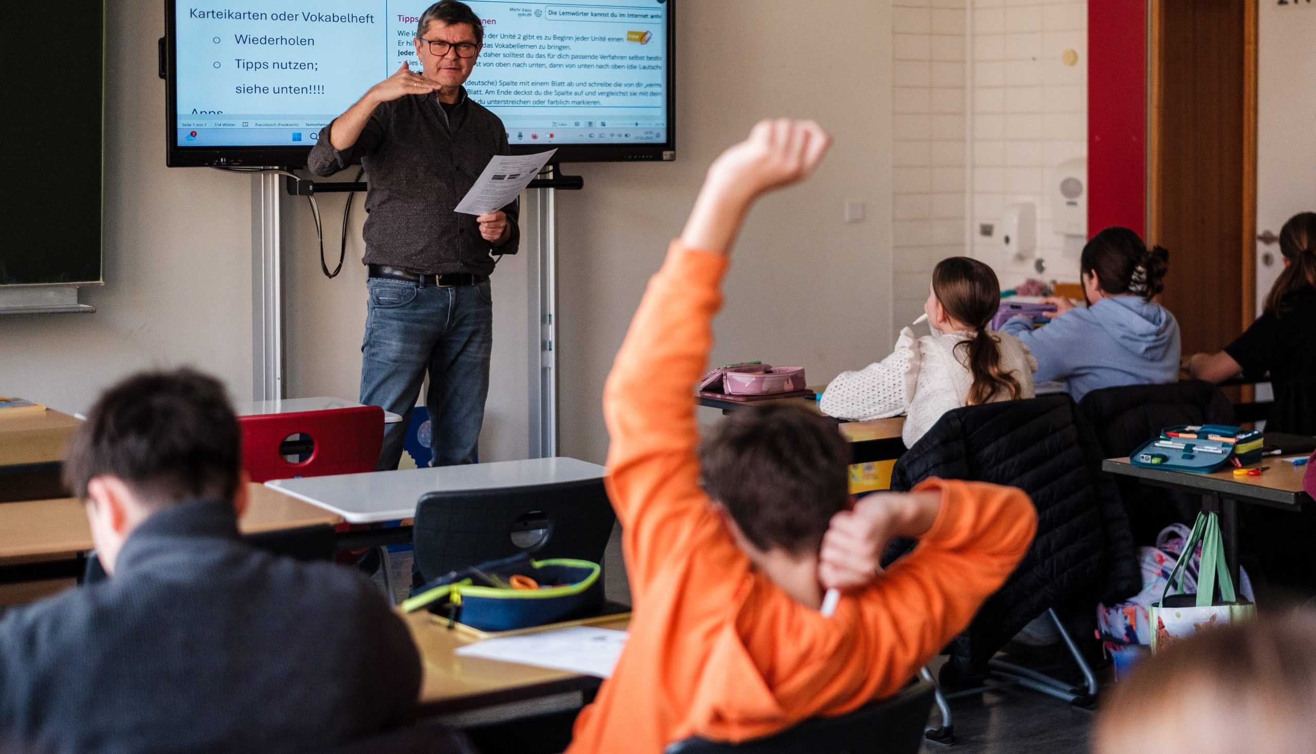 Schüler meldet sich und Lehrkraft erklärt etwas