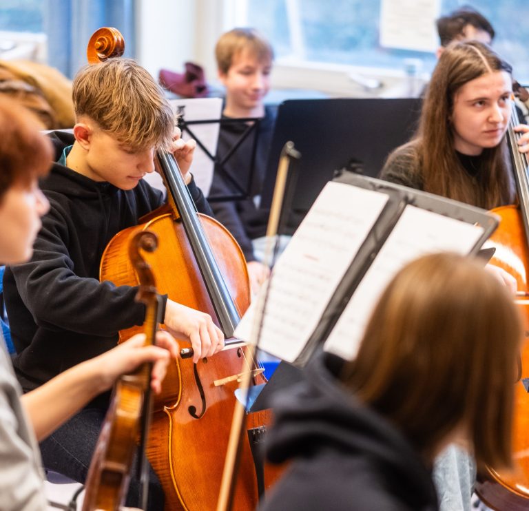 Schülerinnen und Schüler spielen Streichinstrumente