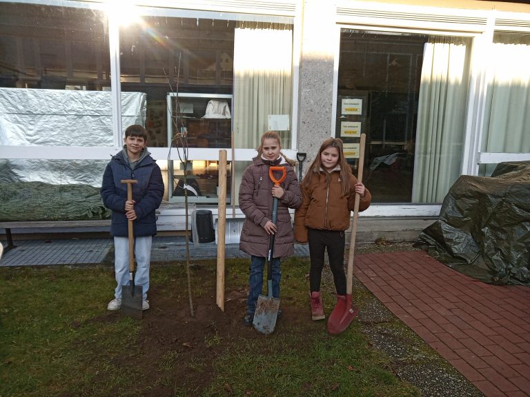Schülergruppe beim Pflanzen des Korbininanapfels