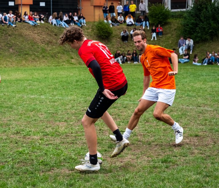 Schüler und Lehrer im Zweikampf beim Fußball
