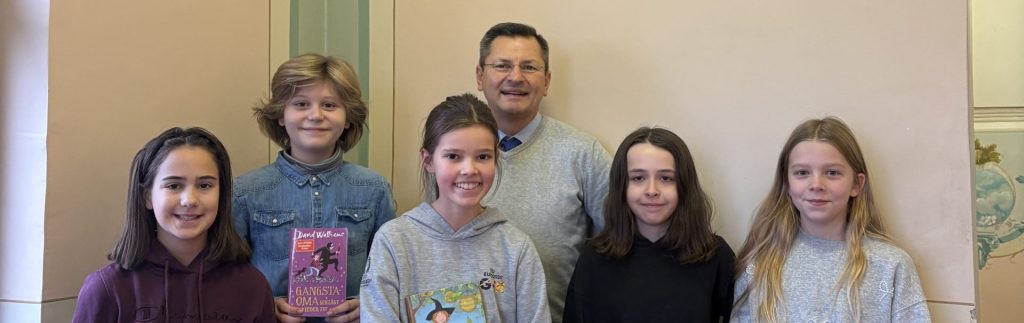 Schulleiter und Schülerinnen präsentieren ihre Bücher