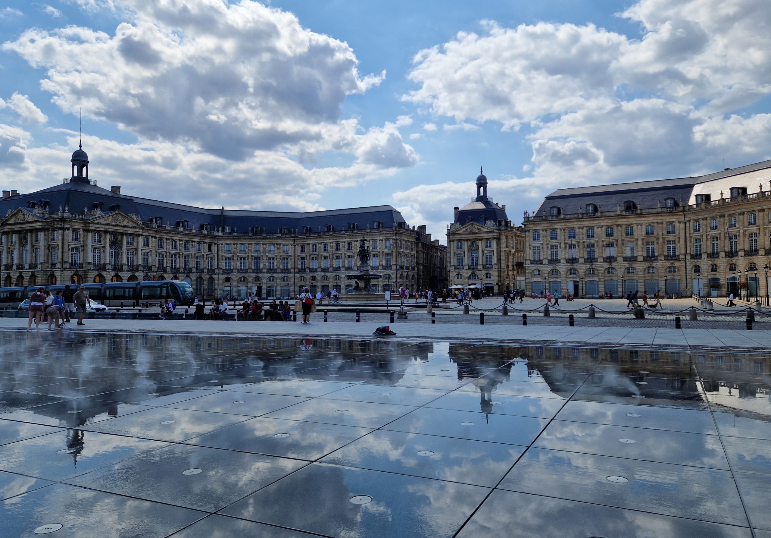 Repräsentatives Gebäude, blauer Himmel mit weißen Wolken, Wasserspiegelung im Vordergrund
