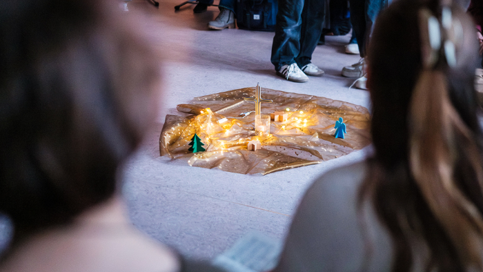 Schüler versammeln sich zur Adventsandacht; Kerzen auf dem Boden