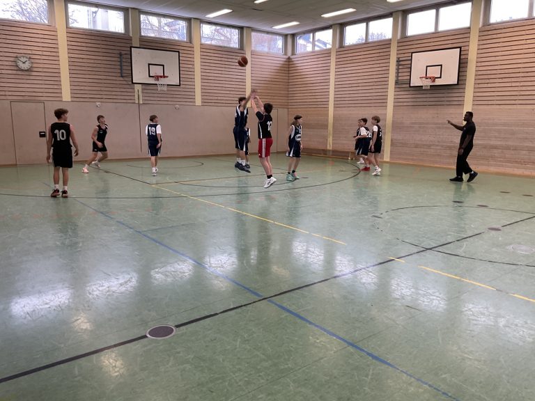 Schüler spielen Basketball in Turnhalle