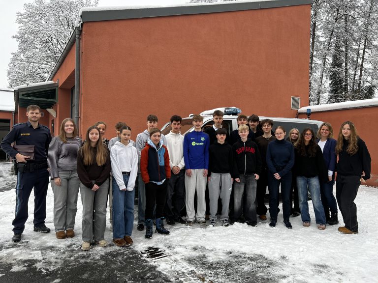Gruppenbild: Schülerinnen und Schüler mit einem Polizisten vor der Polizeiinspektion Kulmbach