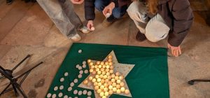 Schülerinnen vor einem Stern aus vielen Teelichtern