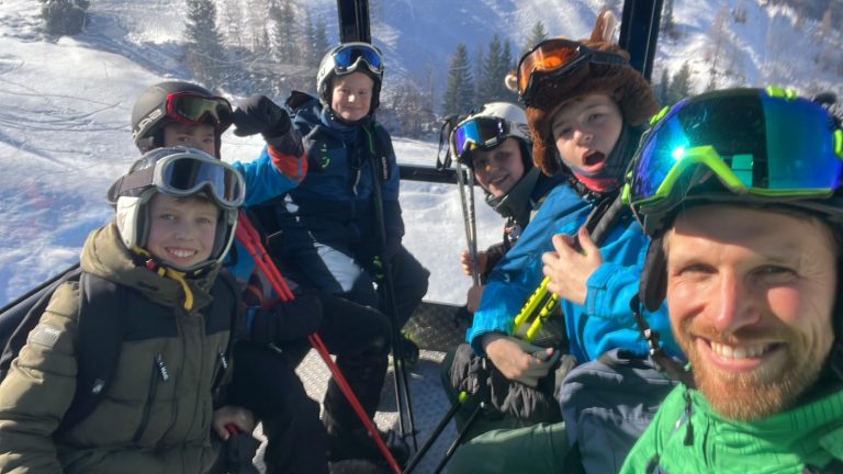 Schülerinnen und Schüler mit Lehrkraft in Skikleidung im Skilift