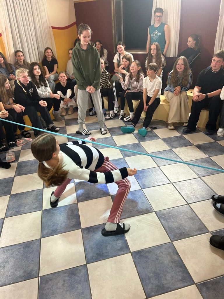 Schülerin beim Limbo; Gruppe von Schülern schaut zu