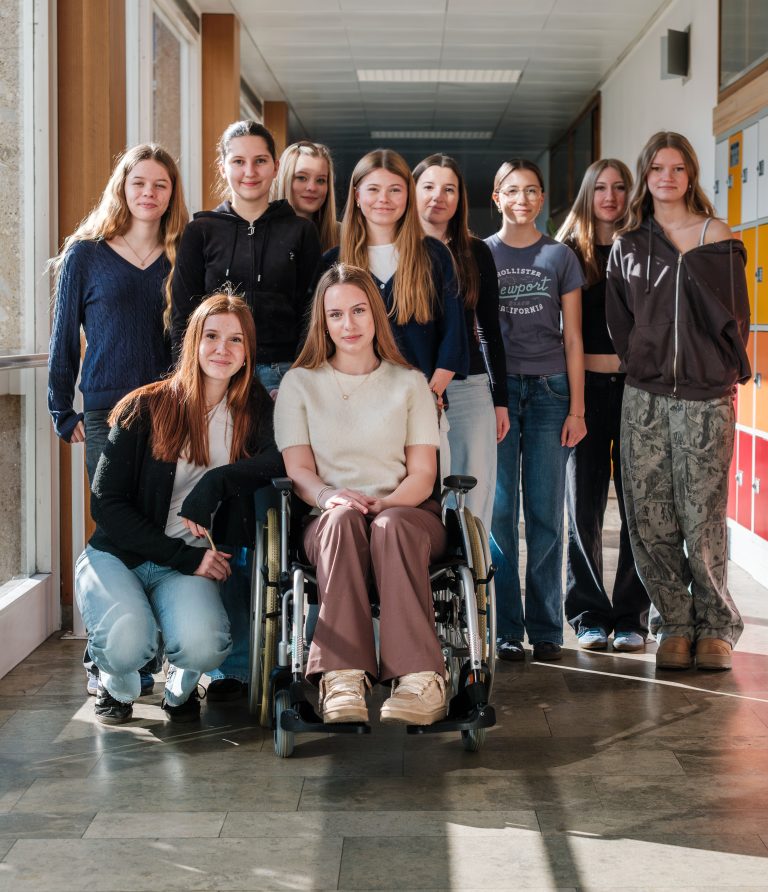 Gruppenfoto von Schülerinnen, die die Zugänglichkeit des Schulgebäudes im Rollstuhl testen