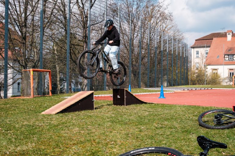 Schüler auf Mountainbike beim Sprung über Rampe