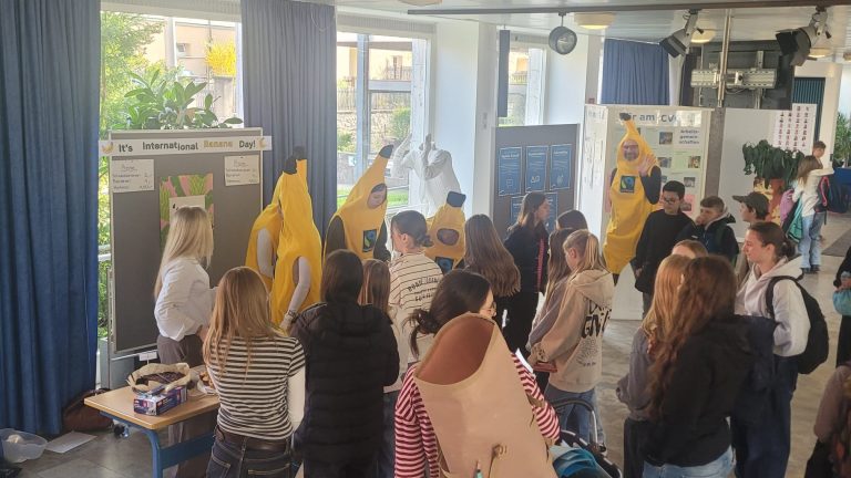 Schülerinnen im Bananenkostüm hinter ihrem Verkaufsstand. Der Stand wird von Schülerinnen und Schülern besucht