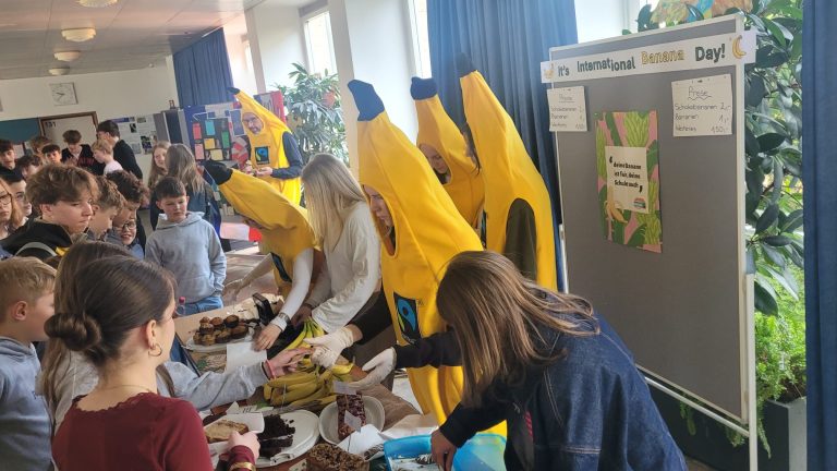 Schülerinnen im Bananenkostüm hinter ihrem Verkaufsstand. Der Stand wird von Schülerinnen und Schülern besucht