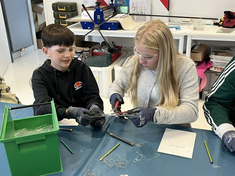 Schülerin und Schüler basteln ein Haus aus Glas