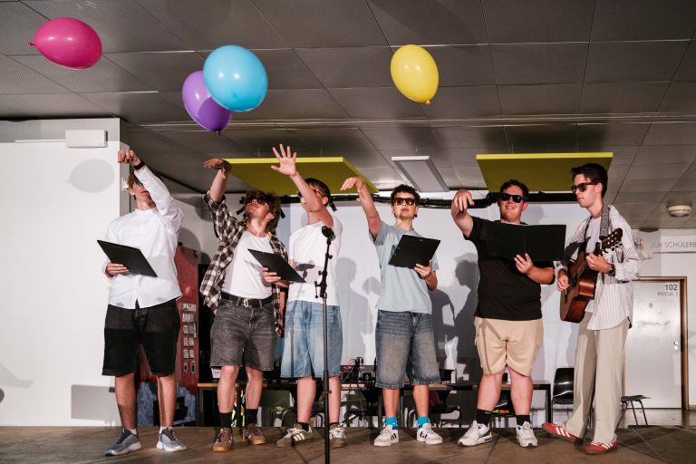 Schüler des Männerchors singen und werfen bunte Luftballons