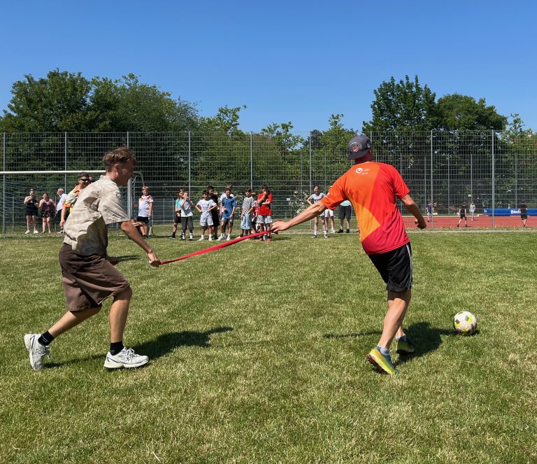 Schüler und Lehrer spielen aneinander gebunden Fußball