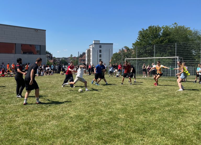 Schüler und Lehrer spielen aneinander gebunden Fußball
