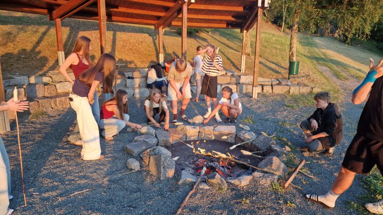 Schülerinnen und Schüler versammelt um eine Lagerfeuerstelle
