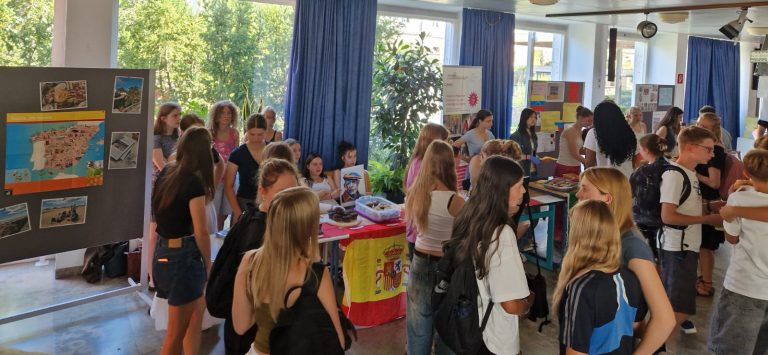 Schülerinnen und Schüler verkaufen Kuchen in der Pausenhalle. Die Tische sind mit spanischen Flaggen dekoriert.