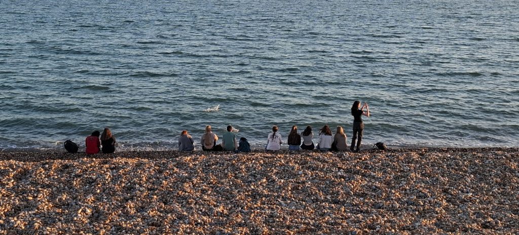 Schülerinnen und Schüler am Strand von Hastings in der Dämmerung
