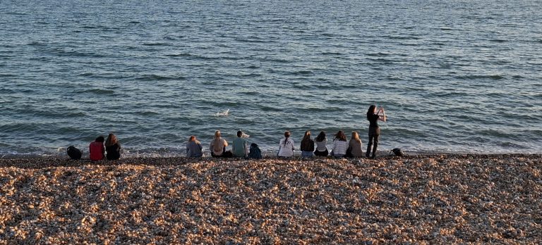 Schülerinnen und Schüler am Strand von Hastings in der Dämmerung