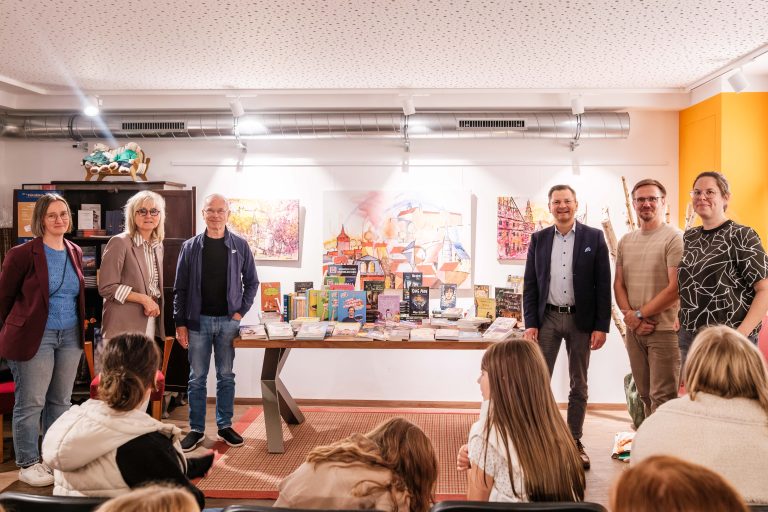 Gruppenfoto von Inhaberin, Schulleiter und Fördervereinsvertretern um den Büchertisch