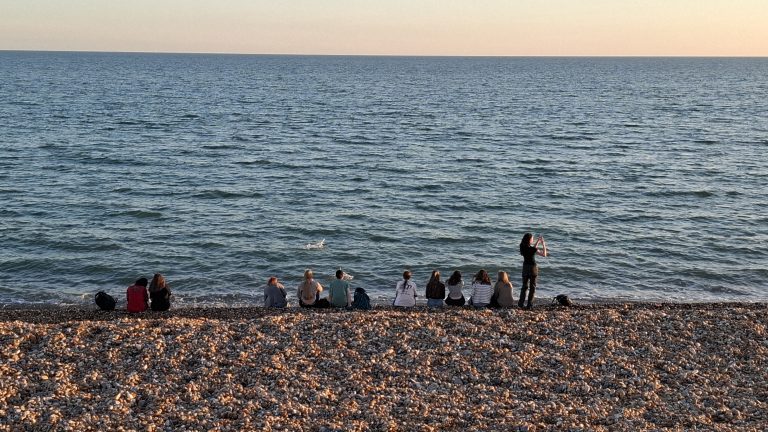 Schülerinnen und Schüler am Strand von Hastings in der Dämmerung
