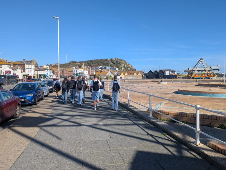 Schülerinnen und Schüler spazieren an der Strandpromenade in Hastings
