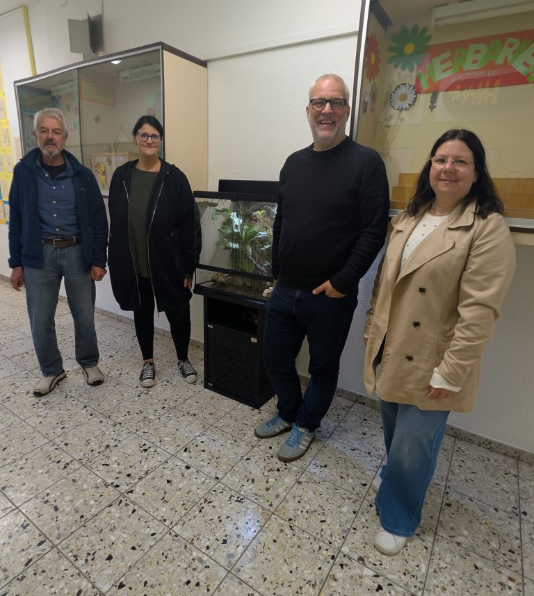 Biologielehrkraft mit Vertretern und Vertreterinnen des Elternbeirats neben dem gespendeten Terrarium
